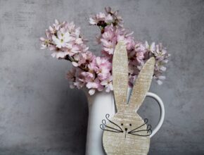 Osterdeko mit Hase und Vase mit blühenden Zweigen