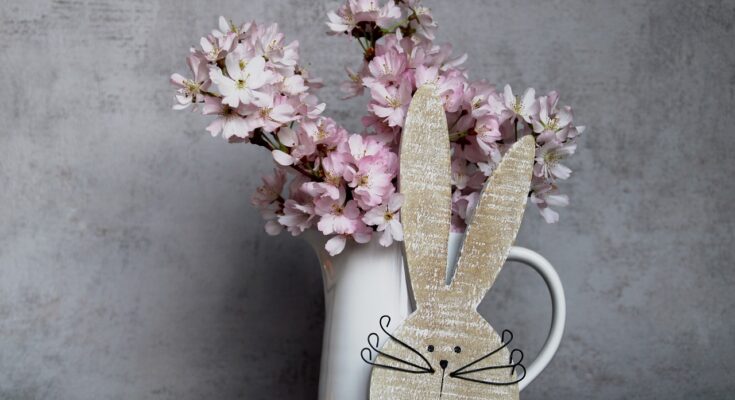 Osterdeko mit Hase und Vase mit blühenden Zweigen