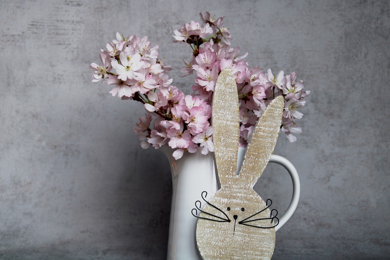 Osterdeko mit Hase und Vase mit blühenden Zweigen