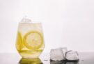 Zitronenwasser mit Zitronenscheiben in einem Glas, daneben Eiswürfel