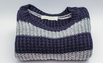 Ein zusammengelegter Strickpulover mit grau-blauen Streifen.