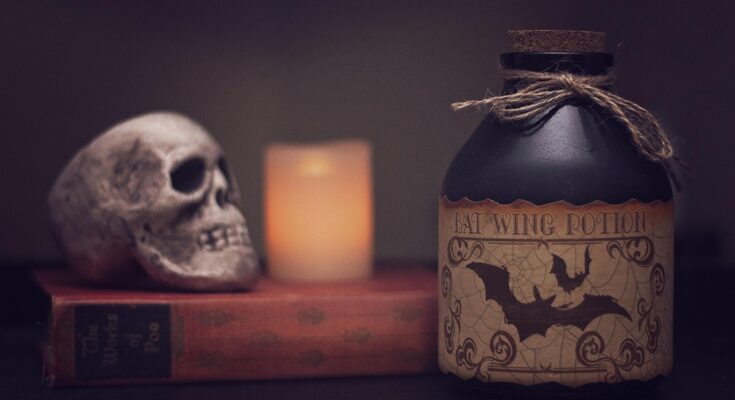 Halloweendeko: Ein Schädel, eine Kerze und daneben eine Flasche mit Gift